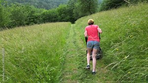 Caucasian female farmer mows a path across the lawn with a motorized lawnmower - Slovenia