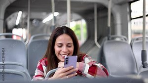 Beautiful, young woman riding in a city bus and using her smartphone