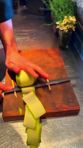 Professional Chef Thinly Slicing Cucumber Strips Using A Sharp Knife and Wooden Board