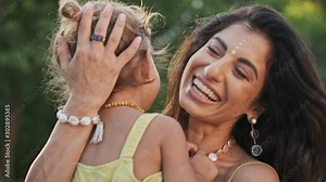 Laughing indian woman having fun with her cheerful child girl outdoors