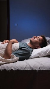 Vertical man sleeping peacefully in bed at night