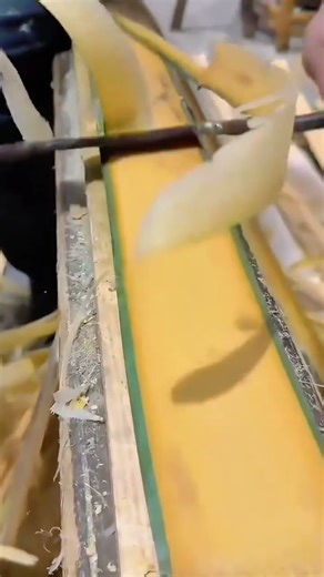 A drawknife tool is used to quickly peel thick shavings from a wooden plank