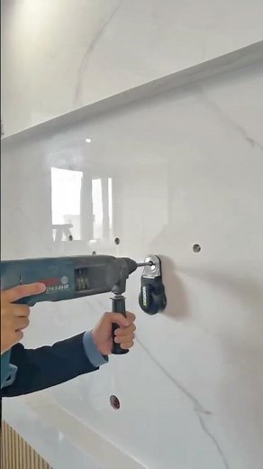Drilling precise holes into a marble wall using an electric rotary hammer for fixture installation