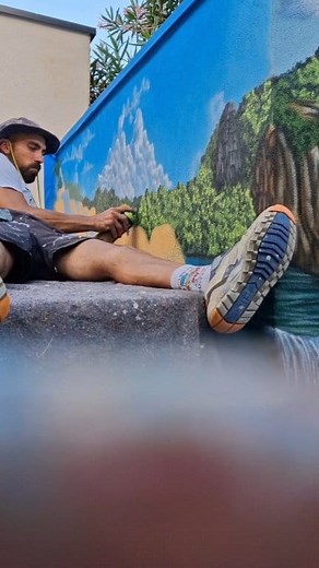 Réalisation à main levée d'une décoration en trompe-l'œil sur un espace légèrement restreint. Les clients voulaient un décor lumineux avec un paysage cascade et mer. 2 éléments étaient intégrés dans le mur, il fallait donc trouver une idée pour les masquer. L'idée était vite réfléchie en mettant ses 2 vieux poteaux en bois pour en faire une perspective donnant sur une plage. Ça donne un effet d'agrandissement à cette petite cour qui en avait besoin. Merci pour leurs confiances et leur gentilless