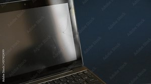 The screen laptop cracked and damaged. A silver laptop with a broken tablet with a cracked display. A close-up picture of part of broken laptop and cracked screen on a classic blue background