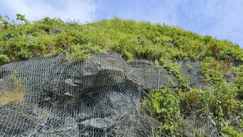 clip-4038295015-rockfall-prevention-net-covering-steep-rocky-cliff