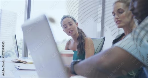 Man opening laptop and navigating slides in business meeting while colleagues discussing charts
