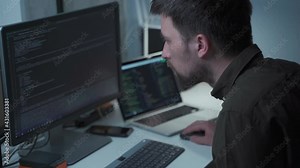 Programming. Man working on computer in IT sitting at work table with PC and laptop, writing codes. Programmer entering data code, working on project in software development company. IT developer