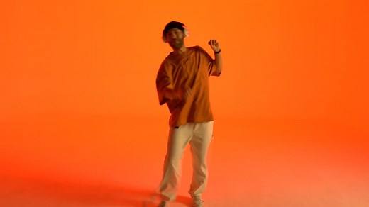 Cheerful dancing of a young man on an orange background - Free Stock Video