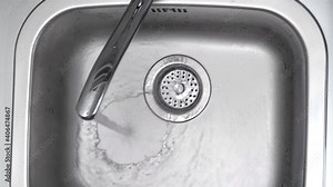 Streaming water in sink. Water stream going down the drain.