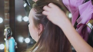 Hairdresser using a hair dryer with professional drying technique at modern beauty salon, close-up.