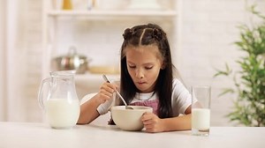 cute little girl eating breakfast: cereal with the milk. healthy breakfast