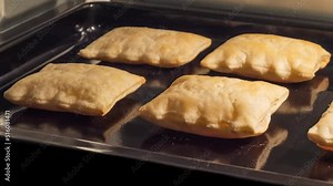Timelapse - puff pastry baking and rising on tray in electric oven in kitchen at home - close up view. Homemade bakery, food, cooking, pastry and time lapse concept