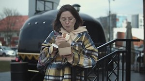 Very hungry woman eating a taco at a taco truck. Stylish woman in outwear is eating lunch from a food truck vendor
