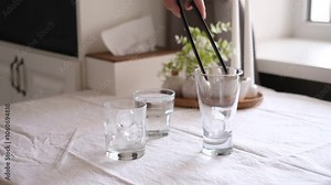 woman putting ice cubes into an empty glass