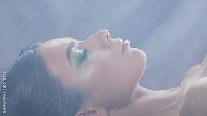 beautiful, charming, gorgeous Oriental girl lies with her eyes open, then closes her eyes. the room in smoke. close up