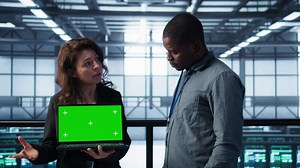 Data center IT team automating routine maintenance tasks with green screen laptop, executing diagnostic scripts. Server room coworkers using mockup notebook, adjusting power settings, camera B