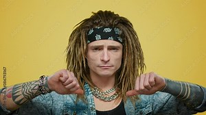Serious rocker looking at camera. Man pointing hands on himself in studio