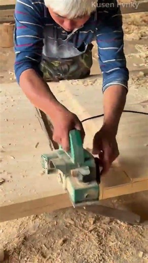 Shaving and smoothing a wide bright wooden plank surface using an electric hand planer power tool
