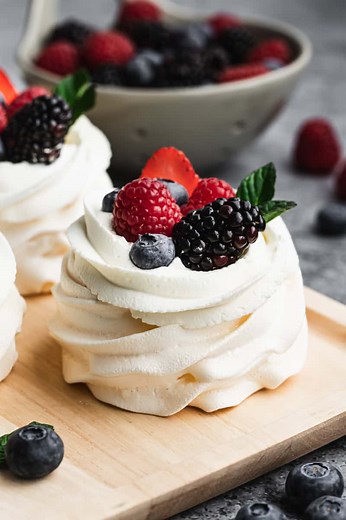 This Mini Pavlova recipe is as delicious as it is beautiful! A light, whipped meringue mixture baked then topped with whipped cream and fresh berries. It has a delicate, crisp exterior with a marshmallow-like center. It’s everyone’s favorite dessert! | Tastes Better From Scratch