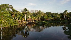 Scenic aerial view of tropical rainforest jungle village at sunrise from the river