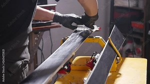 Ski or snowboard tuning and reapair concept. Winter shop worker doing base repair and service