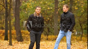 Two young men talking and walking in the autumn park
