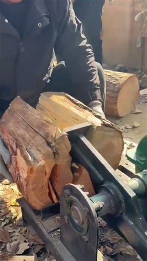 worker is splitting wood log using a wood splitter
