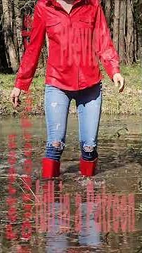 A girl in red rubber boots plays in a puddle
