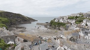 Port Isaac , England , United Kingdom (UK) - 07 01 2024: Aerial view of Port Isaac harbor as seagulls fly over the village and boats docked on the shoreline, surrounded by cliffs and green hills, Corn