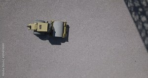 Filmed from above how a yellow single-cylinder asphalt roller works on a construction site.