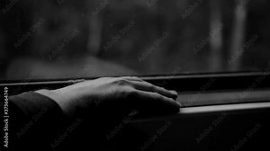 A guy rides a train and taps his fingers on the window sill. Nice close-up.