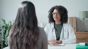 Video of beautiful cheerful female doctor talking while explaining medical treatment to patient in the consultation.