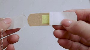 A man opens a Adhesive plaster. First aid for trauma. The medicine. Isolated background. Video