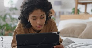 young woman using tablet computer relaxing on bed browsing internet typing social media messages online with mobile touchscreen technology 4k footage