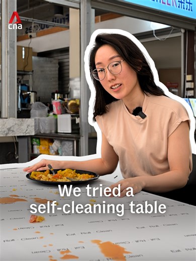 A self-cleaning table is being tested at a food court in NTU. With the press of a button, a moving sheet sweeps leftover food and spilled drinks into a collection tray, resetting the table for the next diner. The idea is to improve hygiene and reduce reliance on manpower. Students and cleaners shared mixed reactions, from concerns about space and design, to whether it could actually make cleaning easier during peak hours. (Video: CNA/Tan Wen Lin) #singapore #singaporenews