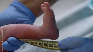 Measuring the newborn's height. Close up of a baby's tiny foot with measuring tape held by the doctor. Close up.