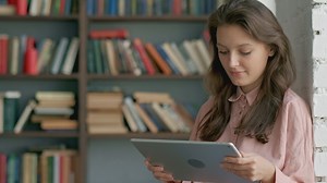 Student reading on a tablet at a library - Free Stock Video
