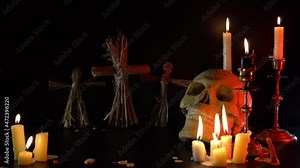 Old Skull and candle with incense on old altar plate which has dim light. Select focus, black background. Straw voodoo dolls. Copy space