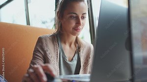 Young smiling woman using portable laptop computer. Female freelancer or student scrolling mouse and typing keyboard, searching, surfing or looking content at laptop Stock Video