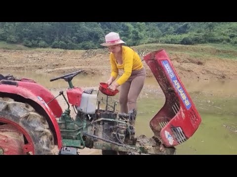 The beautiful girl is busy rescuing the tractor by the river