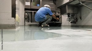 Construction workers are painting the floor using the method self-leveling epoxy.spreading self leveling compound with trowel.Self-leveling epoxy. Leveling with a mixture of cement floors.