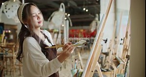Beautiful asian stylish female artist painting picture in art studio. Young woman painter draws with paint brush and oil colors creating artwork sunset landscape on canvas. imagination and creativity.