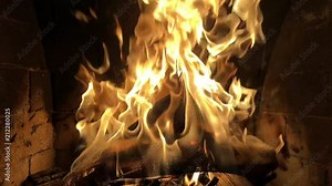Slow-mo of a large fire burning. The flames are largely orange, and rise up dramatically. The atmosphere is very warm.