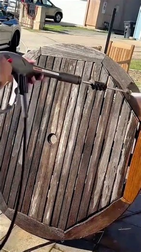Hand using metal tool to restore weathered wooden table