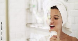 Woman singing and dancing after shower in the bathroom, doing happy dance after body care and cleaning skin in house. Funny and crazy dancer and singer with smile, fun and skin care in the morning