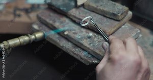 jeweler solders a silver blank with a gas burner in the process of creating a jewelry ring