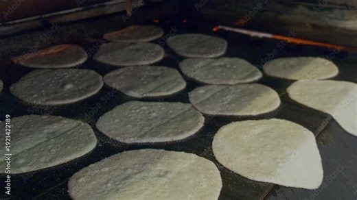 Close-up footage of traditional egyptian flatbread aish baladi baking in conveyor oven. Baking pita bread on traditional egyptian street baker shop