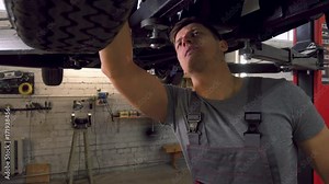 Mechanic working on classic car wheels and suspension in restoration workshop