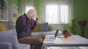 Frustrated old man working on laptop at home. Frustrated and senile old man working on laptop and surprised by what he sees on screen.